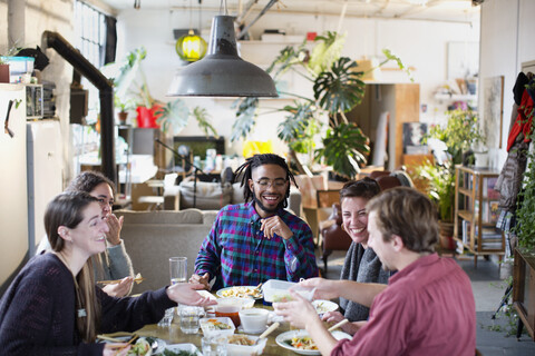 Junge Erwachsene Mitbewohner Freunde genießen Essen zum Mitnehmen am Küchentisch in der Wohnung, lizenzfreies Stockfoto