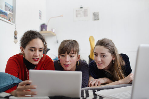 Junge Freundinnen teilen sich ein digitales Tablet auf dem Bett - HOXF04115