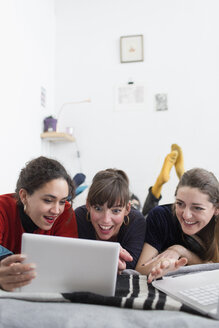 Junge Frauen, die auf dem Bett abhängen und ein digitales Tablet benutzen - HOXF04121