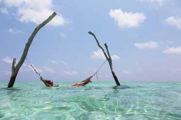 Frau liegt in Hängematte über dem ruhigen Ozean, Malediven, Indischer Ozean - HOXF04142