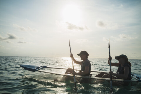 Women in clear bottom canoe on sunny ocean, Maldives, Indian Ocean stock photo