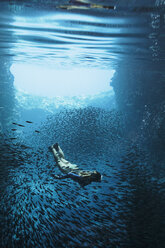 Young woman snorkeling underwater among schools of fish, Vava'u, Tonga, Pacific Ocean - HOXF04153