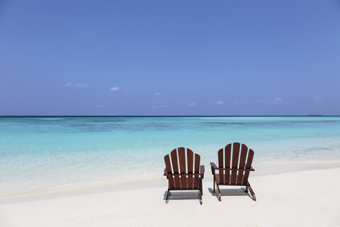 Two adirondack chairs on sunny, tranquil beach overlooking blue ocean, Maldives, Indian Ocean stock photo