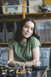 Portrait of smiling female student sitting with science project at desk in classroom at high school - MASF09286