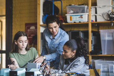 Weibliche Lehrerin hilft Schülern bei der Vorbereitung eines Roboters auf dem Schreibtisch im Klassenzimmer - MASF09294