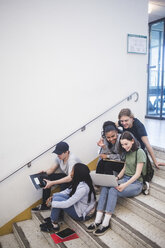 Volle Länge von glücklichen multiethnischen Schülern, die sich unterhalten und auf den Stufen einer High School sitzen - MASF09304