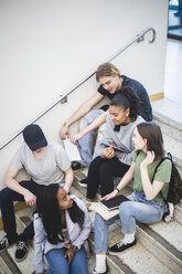 Blick von oben auf multiethnische Schüler, die sich unterhalten und auf den Stufen einer High School sitzen - MASF09305