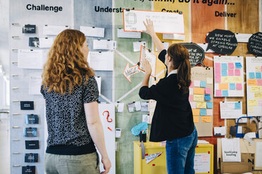 Weibliche Kollegen diskutieren über Strategie an der Wand im Kreativbüro - MASF09322