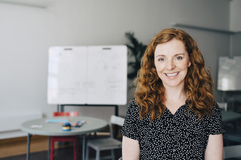Portrait of confident redhead businesswoman standing at creative office - MASF09333