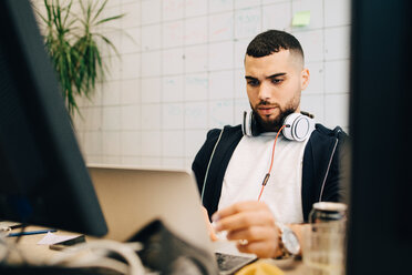 Junger männlicher Computerprogrammierer, der in einem kreativen Büro am Laptop programmiert - MASF09376