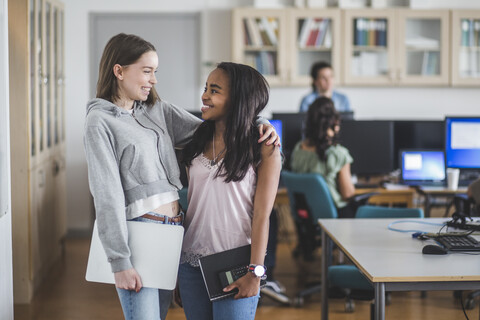 Smiling female students standing in computer lab at high school stock photo