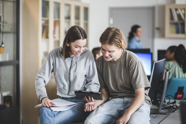 Gymnasiasten teilen sich ein digitales Tablet, während sie im Computerraum auf dem Schreibtisch sitzen - MASF09437