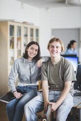 Portrait of smiling high school students sitting on desk in computer lab - MASF09440