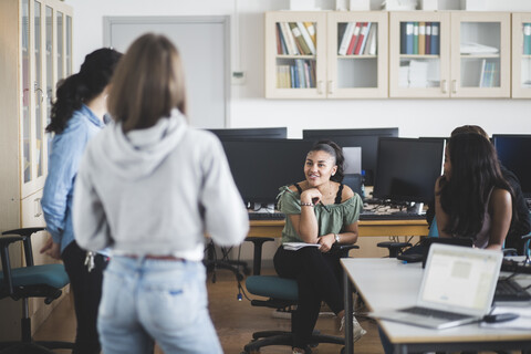 Smiling female high school students with teacher in computer lab stock photo