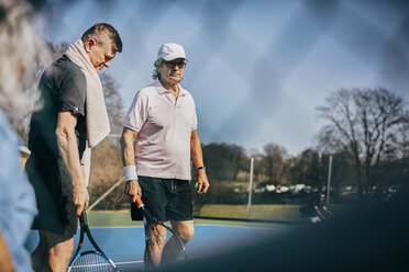 Ältere männliche Freunde mit Schlägern auf dem Tennisplatz - MASF09479