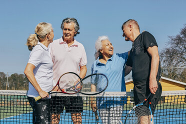 Glückliche männliche und weibliche Senioren grüßen auf dem Tennisplatz vor einem klaren Himmel - MASF09486