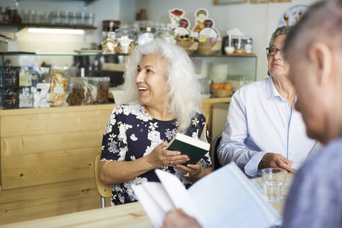 Älterer Mann und Frau mit Büchern sitzen am Tisch in einem Café - MASF09494