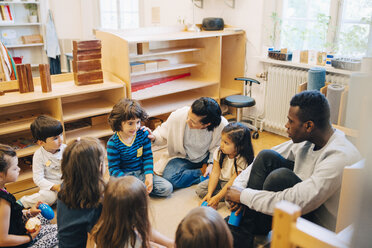 High angle view of teachers and students sitting in child care classroom - MASF09513