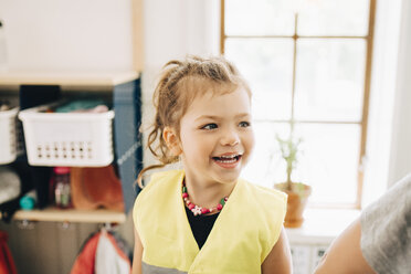 Lächelndes Mädchen, das wegschaut, während es in der Garderobe des Kindergartens steht - MASF09515