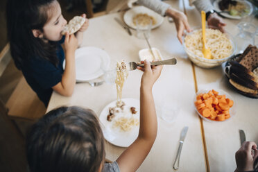 Hochformatige Ansicht von Schülern beim Mittagessen am Tisch im Klassenzimmer - MASF09557