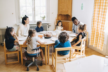 Lehrer und Schüler sitzen während der Mittagspause im Klassenzimmer am Tisch - MASF09560