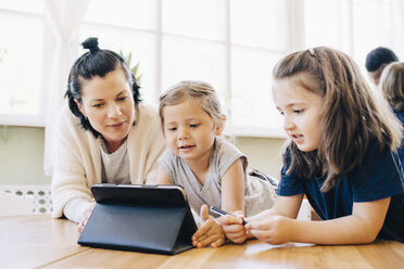 Lehrerin und Schüler betrachten ein digitales Tablet im Klassenzimmer - MASF09572