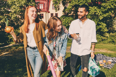 Fröhliche junge Freunde genießen ein Picknick im Hinterhof während des Sommers - MASF09588