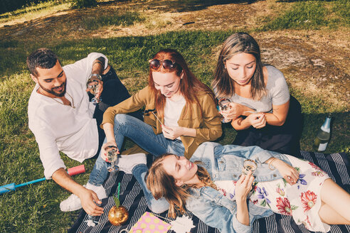 Hohe Winkel Ansicht der glücklichen jungen multiethnischen Freunde genießen Picknick im Hinterhof im Sommer - MASF09592