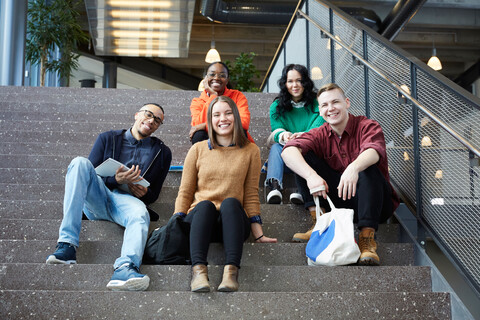 Porträt von lächelnden Studenten, die auf den Stufen einer Universität sitzen, lizenzfreies Stockfoto