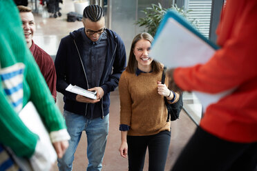 Friends talking to female students standing in university - MASF09653