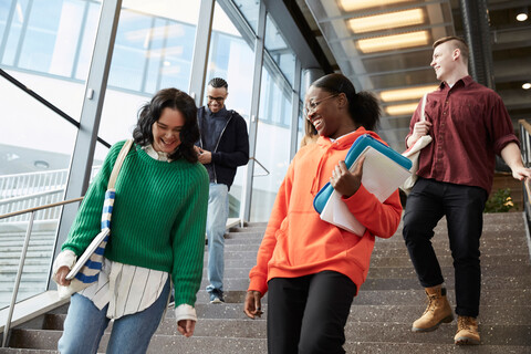 Niedriger Blickwinkel auf glückliche Universitätsstudenten, die die Treppe hinuntergehen, lizenzfreies Stockfoto