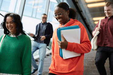 Low angle view of happy students walking down on steps in university - MASF09659