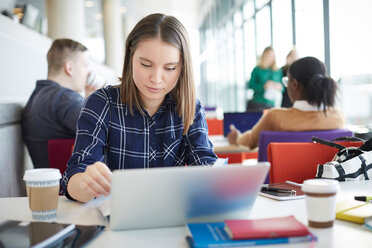 Studentin mit Laptop am Tisch mit Freunden im Hintergrund - MASF09665