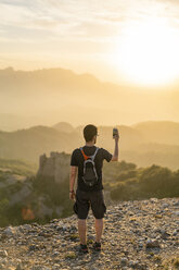 Spain, Barcelona, Natural Park of Sant Llorenc, man hiking and taking a picture of the view at sunset - AFVF01888