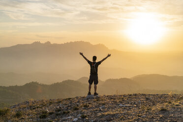 Spain, Barcelona, Natural Park of Sant Llorenc, man hiking and cheering at sunset - AFVF01890