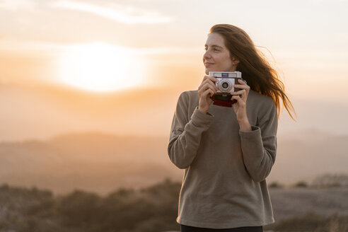 Spanien, Barcelona, Naturpark Sant Llorenc, Frau mit alter Kamera bei Sonnenuntergang - AFVF01899