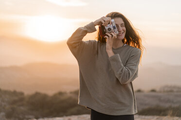 Spanien, Barcelona, Naturpark Sant Llorenc, Frau fotografiert mit alter Kamera bei Sonnenuntergang - AFVF01900