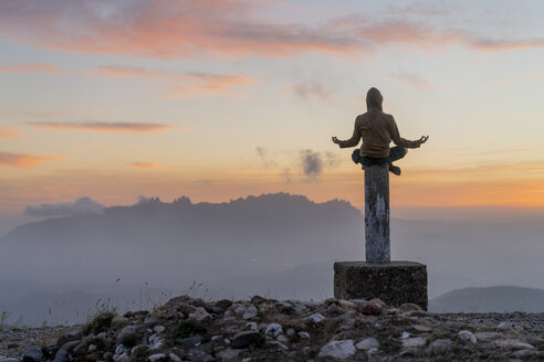 Spanien, Barcelona, Naturpark Sant Llorenc, Mann in Yoga-Pose auf Stange bei Sonnenuntergang sitzend - AFVF01906