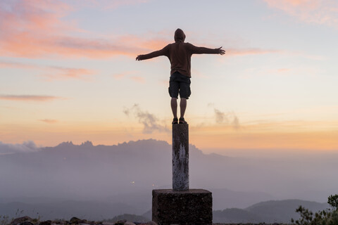 Spanien, Barcelona, Naturpark Sant Llorenc, Mann steht bei Sonnenuntergang auf einem Pfahl, lizenzfreies Stockfoto