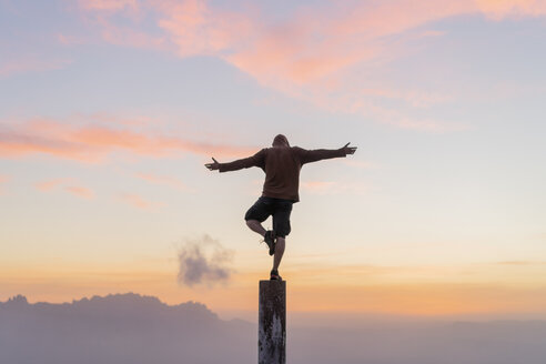 Spain, Barcelona, Natural Park of Sant Llorenc, man standing on pole at sunset - AFVF01908