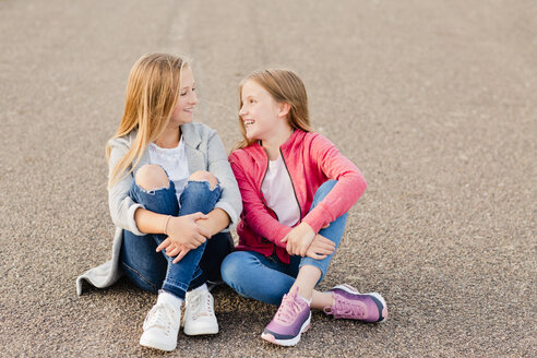 Zwei lächelnde Mädchen sitzen nebeneinander auf dem Boden - NMSF00276