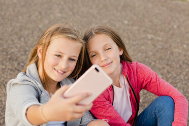 Porträt von zwei lächelnden Mädchen, die ein Selfie mit einem Smartphone machen - NMSF00278