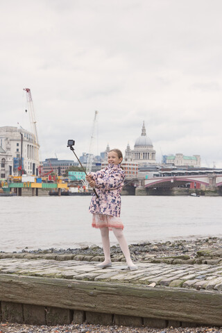 UK, London, glückliches Mädchen macht Selfie vor der Themse, lizenzfreies Stockfoto