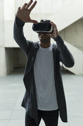 Young man wearing Virtual Reality Glasses raising his hand - JPTF00052