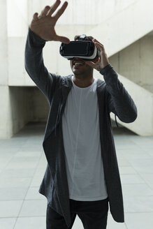 Junger Mann mit Virtual-Reality-Brille hebt seine Hand - JPTF00052