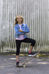 Portrait of smiling blond girl with skateboard - JFEF00906