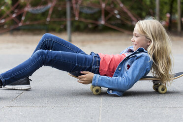 Smiling blond girl with skateboard on playground - JFEF00915