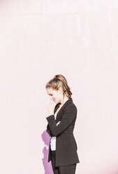 Lächelnde junge Frau vor rosa Wand stehend - UUF15679