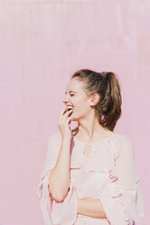 Lachende junge Frau vor einer rosa Wand - UUF15734