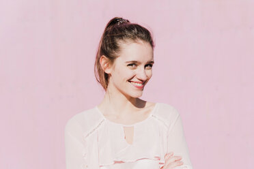Porträt einer lächelnden jungen Frau vor einer rosa Wand - UUF15738
